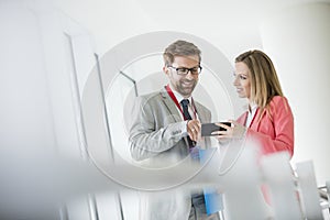 Smiling business people using smart phone in convention center