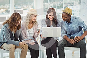 Smiling business people using technology while discussing