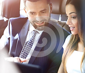 Smiling business people working in backseat of car