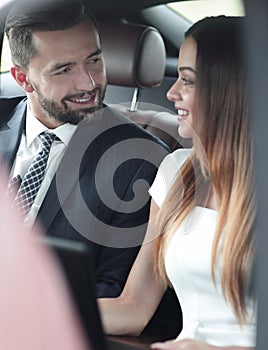 Smiling business people working in backseat of car