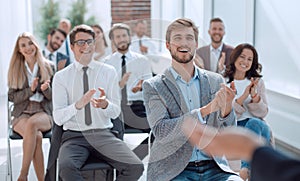 Smiling business seminar listeners applauding the speaker