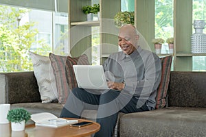 Smiling business senior old elderly Black American man, African person working from home on table with computer notebook laptop in