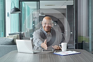 Smiling business senior old elderly Black American man, African person working from home on table with computer notebook laptop in