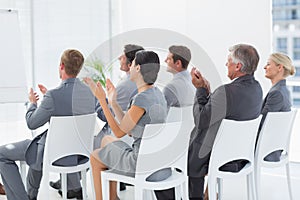 Smiling business team applauding during conference