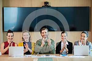 Smiling business team applauding during meeting in conference room