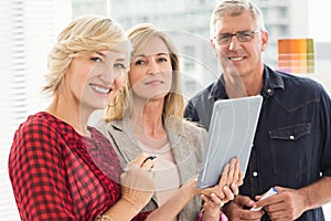 Smiling business team holding a tablet