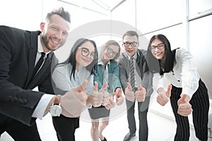 Smiling business team looking at the camera and showing thumbs up