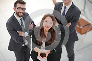 Smiling business team shows a fresh sprout