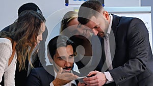 Smiling business team working with smartphone, watching somethng interesting in office