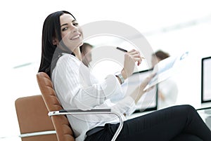 Smiling business woman with financial documents sitting at work desk.