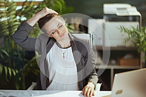 smiling business woman in green office stretching neck