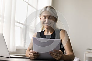 Smiling business woman hold papers read good news