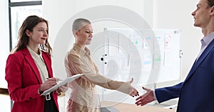 Smiling business woman and man shaking hands while standing in office