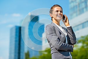 Smiling business woman in office district talking cellphone