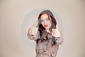 Smiling business woman pointing away while looking at the camera over gray background