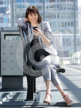 Smiling business woman reading text message on mobile phone