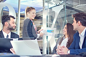 Smiling business woman showing graphs to her colleagues at business meeting in the office.