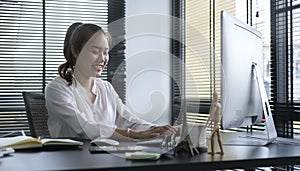 Smiling business woman sitting in bright modern office and working with computer