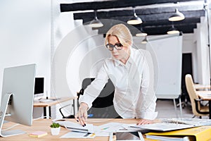 Smiling business woman standing and looking on computer diplay