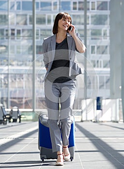 Smiling business woman talking on mobile phone at airport