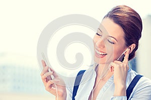 Smiling business woman walking on street listening to music on mobile phone