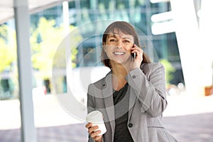 Smiling business woman walking and talking on cell phone