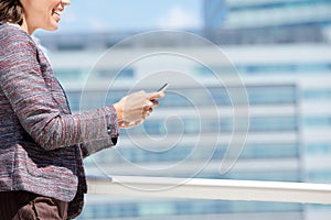 Smiling business woman walking and using mobile phone