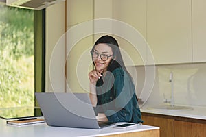 Smiling business woman working from home with laptop, smartphone and notebook