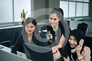 Smiling business women team working at office desk and discussing a project on computer