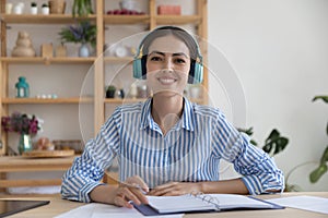 Smiling businesslady in headphones sit at desk look at camera photo