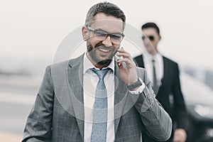 smiling businessman with bodyguard talking