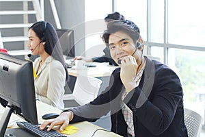 Smiling Businessman Call Center and technical Support staff with headset talking and Typing keyboard for job. Asian customer