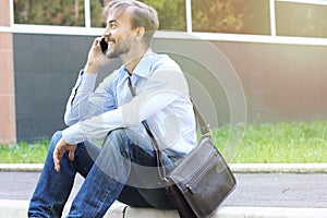 Smiling businessman in casual clothes with leather brief bag sit