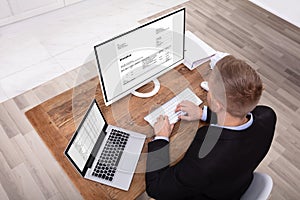 Smiling Businessman Checking Invoice On Computer