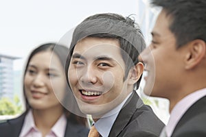 Smiling businessman with colleagues looking at camera