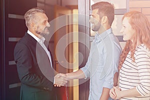 Businessman congratulating happy couple buying flat photo