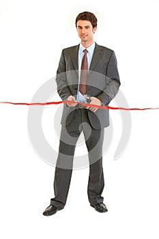 Smiling businessman cutting cutting red ribbon