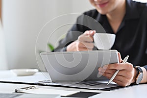 Businessman drinking coffee and reading news on digital tablet.