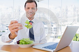 Smiling businessman eating a salad
