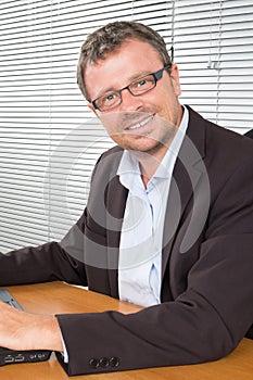 Smiling businessman in eyeglasses with laptop computer office