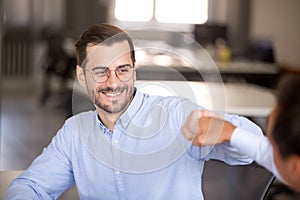 Smiling businessman give fist bump to colleague celebrating win