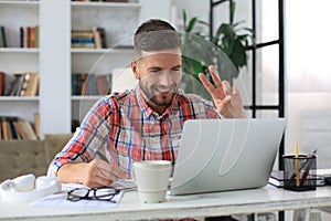 Smiling businessman greeting colleagues in video conference and negotiating distantly from home photo