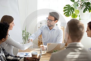 Smiling businessman handshake female employee at meeting