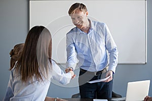 Smiling businessman handshake female worker greeting with promot