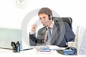 Smiling businessman with headset sitting at desk