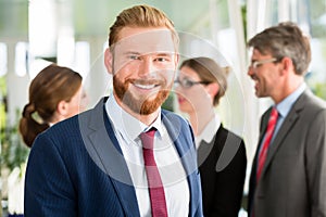 Smiling businessman and his team in the background