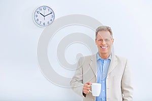 Smiling businessman holding a cup of coffee photo