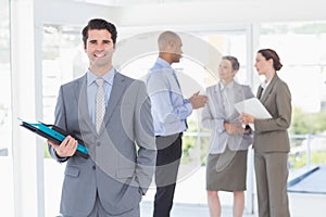 Smiling businessman holding files and looking at camera