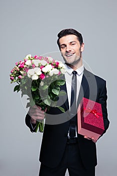 Smiling businessman holding flowers and gift box