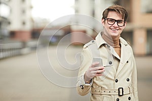 Smiling Businessman Holding Smartphone Outdoors in City